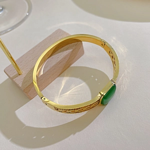 Vintage gold stainless steel bangle with an oval green gemstone and chain relief pattern