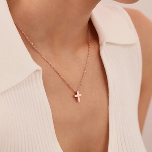 Collier avec pendentif croix en or rose minimaliste porté par un mannequin femme