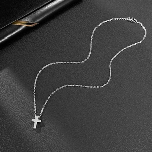 Gros plan du pendentif croix argenté minimaliste sur fond de cuir noir