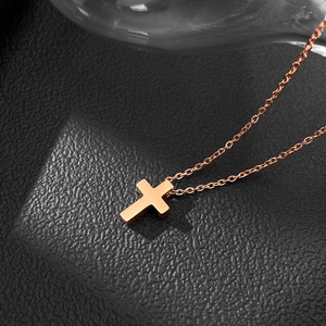 Gros plan du pendentif croix en or rose sur fond de cuir noir avec effet de lumière