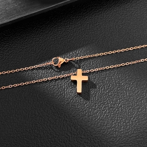 Gros plan détaillé d'un pendentif croix minimaliste en or rose sur texture noire