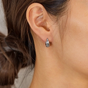 Gros plan de boucles d'oreilles créoles en argent poli portées pour un style épuré