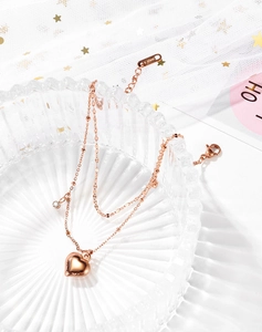 Detail of rose gold double-layer stainless steel anklet with heart and crystal charms