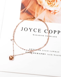 Detail of double-layer rose gold heart anklet with zircons on a fashion magazine background