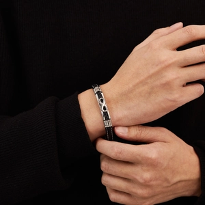 Men's black braided leather bracelet with silver infinity symbol on model's wrist