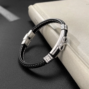 Macro detail of men's braided leather bracelet featuring infinity symbol and metal clasp