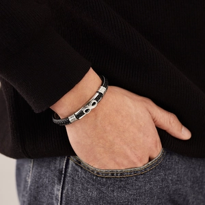 Detail of men's braided black leather bracelet with silver infinity symbol on wrist