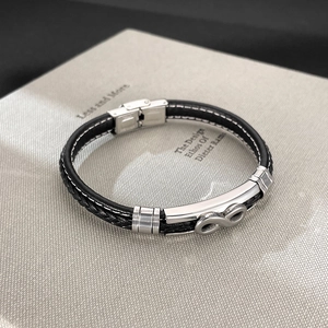 Detail of infinity symbol charm on black braided leather bracelet with metal clasp