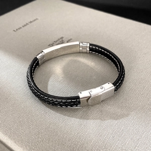 Detail of black woven leather bracelet with contrast stitching and silver metal clasp