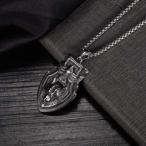 Detailed relief of eagle and wolf head on a stainless steel shield pendant with chain
