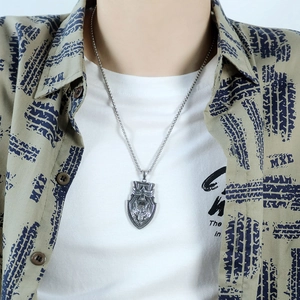 Close-up of a vintage steel shield necklace with a detailed wolf head carving for men