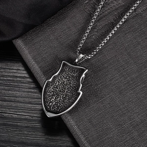Detail of shield pendant with black stone inlay on stainless steel curb chain