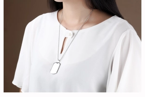 Polished stainless steel dog tag pendant with beaded chain on male model wearing shirt