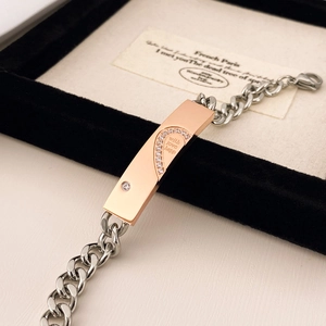 Dettaglio del bracciale a catena con piastra a cuore in oro rosa e incisione in scatola