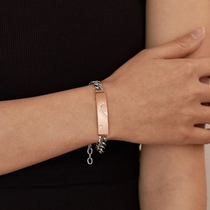 Dettaglio ravvicinato di un bracciale a catena bicolore con intarsio di cristalli a cuore