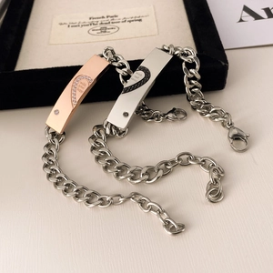 Dettaglio dei bracciali per coppia con design a cuore puzzle in acciaio oro e rosa