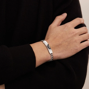 Dettaglio del bracciale a catena cubana d'argento con placca su un polso maschile