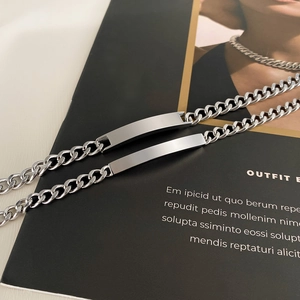 Dettaglio di due bracciali a catena cubana argentati con targhette metalliche rettangolari