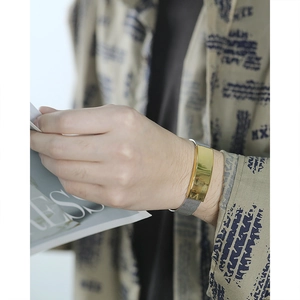Détail du bracelet en maille argentée et plaque en métal doré poli sur le poignet