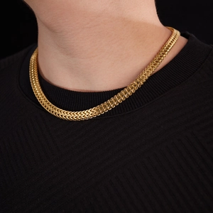 Detail of a men's gold Franco chain necklace showing woven texture on a black sweater