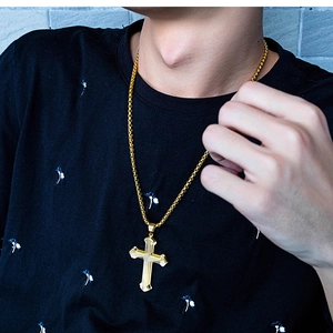 Close-up of a layered golden titanium steel cross necklace on a male model wearing black