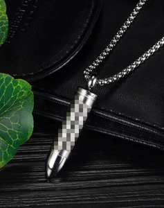 Detailed view of stainless steel bullet pendant necklace on a black leather wallet