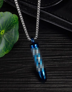 Close-up of a blue bullet pendant necklace on a stainless steel bead chain and wood background