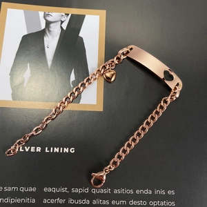 Close-up of rose gold stainless steel Cuban bracelet with heart pendant and engravable plate