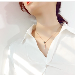 Detail of rose gold necklace featuring heart lock with white enamel and vintage key pendant
