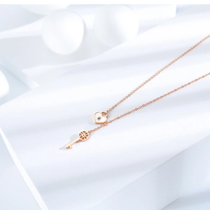 Macro view of rose gold key and heart lock pendant on a minimalist chain