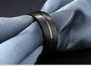 Primer plano de anillo para hombre en acero negro mate con acabado cepillado y surco central