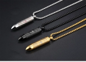 Tres collares con colgante en forma de bala en oro, plata y negro sobre fondo negro