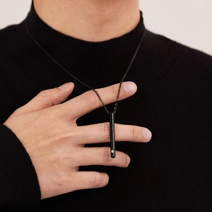 Détail d'un collier pour homme avec pendentif cylindrique noir et un diamant scintillant