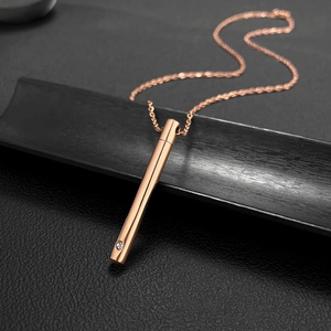 Détail du pendentif cylindrique en or rose avec zircon sur fond de cuir noir