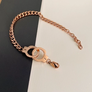 Close-up of rose gold cuff bracelet with Unlock and Put Down engraving on Cuban links