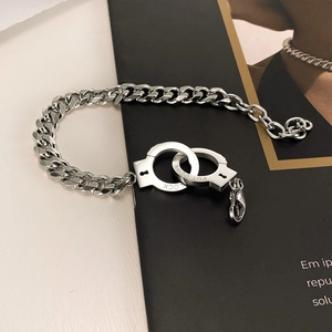 Detail shot of silver cuff link necklace with 'LOCK' and 'PUT DOWN' engravings