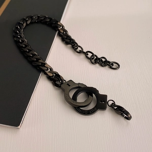 Detail view of black stainless steel handcuff link bracelet with engraved unlock text
