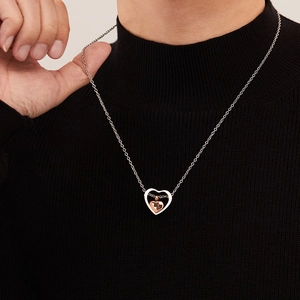 Dettaglio di una collana a cuore bicolore per ceneri indossata su un maglione nero