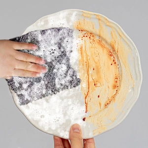 Detail showing stainless steel cleaning mesh effectively removing grease from a ceramic plate