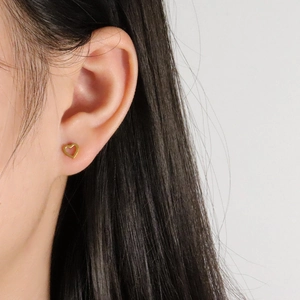 Eleganter goldener hohler Herz-Ohrstecker getragen von einem Model in Nahaufnahme