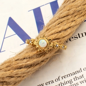 Macro detail of sunburst titanium steel ring with opal stone on rustic hemp rope background