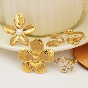 Close-up of a 5-piece gold floral ring set with pearls and rhinestones on a ceramic dish