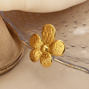 Detailed close-up of golden flower stud earring featuring textured metallic petals finish