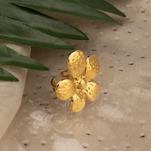 Detailed view of adjustable golden flower ring with hammered texture on fabric