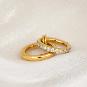 Detalle de anillos entrelazados chapados en oro de 18k con pavé de circonitas brillantes