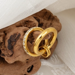 Detalle de anillos de doble capa de oro de 18k con circonitas sobre madera natural