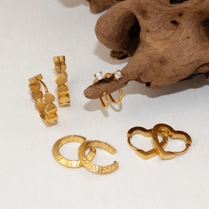 Ensemble de boucles d'oreilles dorées géométriques en U et clous coeur sur bois