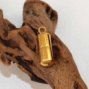 Dettaglio del ciondolo a capsula cilindrica placcato oro 18K su legno antico