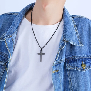 Nahaufnahme einer mattschwarzen Kreuzkette für Herren am Model mit Jeansjacke