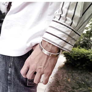 Primer plano de pulsera rígida minimalista de acero plateado mate usada al aire libre